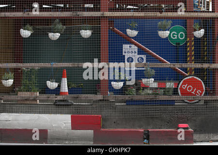 UK-London: Arbeiter harte Hüte als Hängeaufbewahrung für Blumen am Eingang auf Tottenham Court Road Cross Schiene verwendet werden. Aug16 Stockfoto