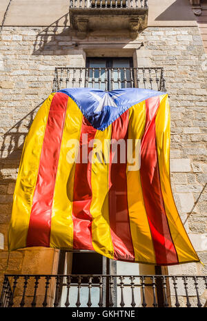 Flagge der Unabhängigkeitsbewegung von Katalonien, genannt Estelada (inoffiziell), winken in einer Straße in der Innenstadt von Girona, Spanien. Stockfoto