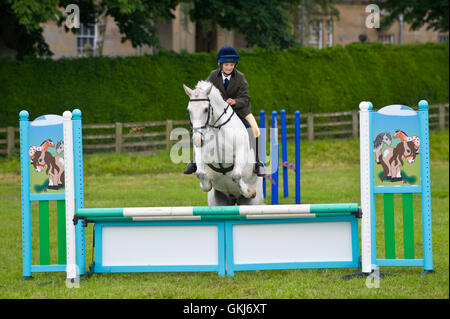 Junges Mädchen & ihr Pony springen Zäune in Golden Valley Ponyclub, Baskerville Hall, Clyro, Powys, Wales, UK Stockfoto