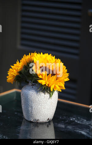 Strauß Sonnenblumen in alten Keramik Krug gegen eine weiße Holzwand. Stockfoto