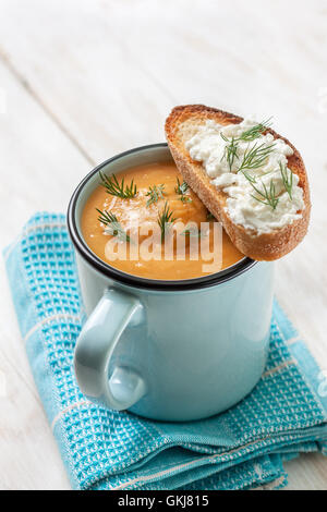 Erbsen Suppe pürieren in einem blauen Becher, Toast mit Frischkäse auf weißem Holz Hintergrund Stockfoto