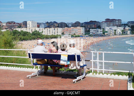 Vier Leute sitzen auf einer Bank am Strand suchen. Piquio Gärten, Santander, Spanien. Stockfoto