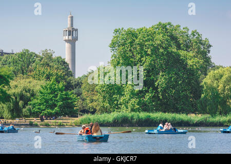 Muslim London, Blick im Sommer auf Touristen in Booten auf dem See mit Bootstouren im Regent's Park mit dem Minarett der Moschee im Hintergrund, London, Großbritannien. Stockfoto