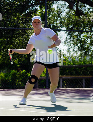 Weibliche College Tennisspieler am gelben Ball schwingen Stockfoto