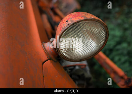 Eine Nahaufnahme eines Scheinwerfers eine alte rostige Traktor in einem Waldgebiet. Stockfoto