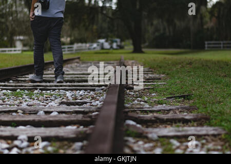 Mann bei einem Spaziergang entlang eines alten aus Verwendung Bahngleis. Soft-Fokus für Titel. Stockfoto