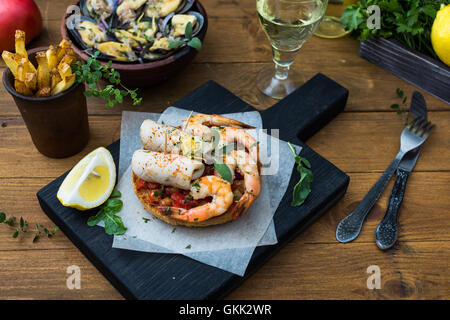 Italienisches Essen. Bruschetta mit Tintenfisch und Garnelen, Tomaten und Petersilie Stockfoto