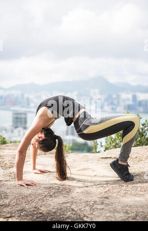 Yoga auf dem Gipfel eines Berges, mit Blick auf die Stadt von Hong Kong. Stockfoto