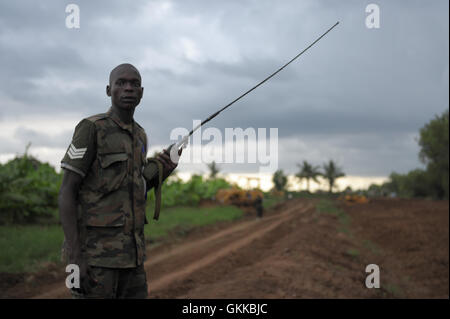 Eine Afrikanische Union Soldat, Zugehörigkeit zu den ugandischen Kontingent von AMISOM, sorgt für Sicherheit während eine Straße in Afgoye, Somalia, am 10. November benotet wird. Als Teil der Anstrengungen zur Verbesserung der Infrastruktur von Somalia und lokale Gemeinschaften zu helfen wird Hilfe derzeit von AMISOM in Afgoye, Herabstufung helfen Straßen der Region gegeben. Afgoye, bekannt als die Kornkammer von Somalia, ist einer der fruchtbarsten Gegenden des Landes und produziert eine Vielzahl von Früchten, sowohl die Bewohner von Mogadischu und für den Export in die Golfregion. AU UN IST Foto / Tobin Jones Stockfoto