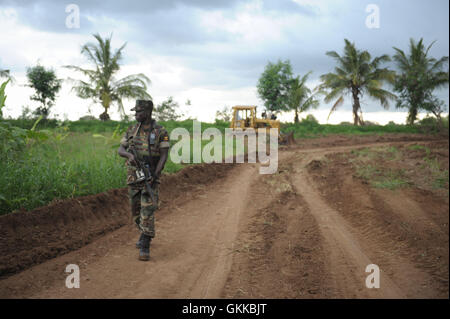 Eine Afrikanische Union Soldat, Zugehörigkeit zu den ugandischen Kontingent von AMISOM, sorgt für Sicherheit während eine Straße in Afgoye, Somalia, am 10. November benotet wird. Als Teil der Anstrengungen zur Verbesserung der Infrastruktur von Somalia und lokale Gemeinschaften zu helfen wird Hilfe derzeit von AMISOM in Afgoye, Herabstufung helfen Straßen der Region gegeben. Afgoye, bekannt als die Kornkammer von Somalia, ist einer der fruchtbarsten Gegenden des Landes und produziert eine Vielzahl von Früchten, sowohl die Bewohner von Mogadischu und für den Export in die Golfregion. AU UN IST Foto / Tobin Jones Stockfoto