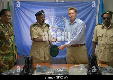 Gefängnis Kommissar General Hussein Hassan Osman erhält eine Baskenmütze, als Symbol für die gesamte Sendung von 144 Uniformen aus dem regionalen Koordinator des UNODC Alan Cole während eines Handovers Uniformen somalischen Sorgeberechtigten Korps am 19. Februar 2014. Stockfoto