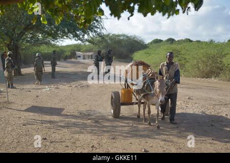 Ein somalischer Mann Wasserholen zurück in seine Heimat geht afrikanischen Unionstruppen während einer Fuß-Patrouille in Qoryooley, Somalia, am 29. April. Die Stadt Qoryooley wurde von al Shbab Kämpfer in einer gemeinsamen Operation vor knapp über einem Monat von afrikanischen Union Kräfte und die Somali National Army erobert. AU UN IST Foto / Tobin Jones Stockfoto