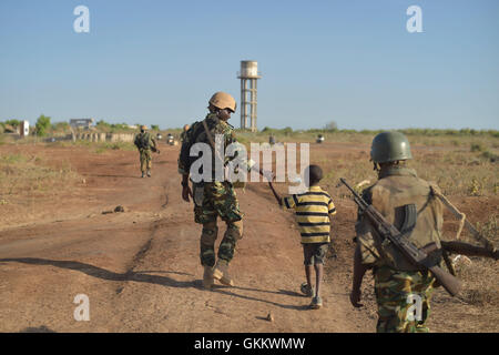 Ein burundischer Soldaten als Teil der Mission der Afrikanischen Union in Somalia, ein kleiner Junge Hand hält in der Nähe der Stadt Mahaday, Somalia, während einer Patrouille. AMISOM Foto / Tobin Jones Stockfoto