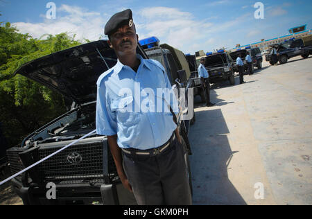 SOMALIA, Mogadischu: Auf einem Foto zur Verfügung gestellt von der Afrikanischen Union Vereinten Nationen Informationen unterstützen Team 7 Mai, ein Offizier mit der somalischen Polizei (SPF) steht vor neuen Pick-up-Trucks vor Übergabe der Ausrüstung, die von der Regierung von Japan durch die politischen Büros der Vereinten Nationen für Somalia (UNPOS) Treuhandfonds zur Unterstützung der Wiederaufbau der SPS in der somalischen Hauptstadt Mogadischu gespendet. Die Geräte enthalten eine motor-Transport-Flotte von 15 Pick-up-Trucks, zwei Truppe Personal trägt und zwei Krankenwagen, 1,800 ballistische Helme und Sätze von Handschellen, über 1.000 Stockfoto