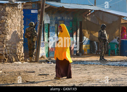 SOMALIA, Belet Mahadday: Auf einem Foto von der hybride Nationen Informationen Support Team 17 November veröffentlicht, überquert eine somalische Mädchen eine Straße auf dem Weg zur Schule während Soldaten die Djiboutian Kontingent dienen mit der Mission der Afrikanischen Union in Somalia (AMISOM) auf einer Straße in der zentralen somalischen Stadt von Belet Weyne in der Hiraan Region von Somalia Wache , ca. 300km nordwestlich der Hauptstadt Mogadischu. Dschibutischer AMISOM Truppen führen täglich, am frühen Morgen fegt der Bereiche der Stadt auf der Suche nach improvised explosive Devices (IED) von Al-Qaida-Afflliated Al gepflanzt Stockfoto