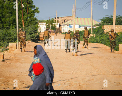 SOMALIA, Belet Weyne: Auf einem Foto von der hybride Nationen Informationen Support Team 17 November veröffentlicht, eine somalische Frau überquert eine Straße während Soldaten die Djiboutian Kontingent dienen mit der Mission der Afrikanischen Union in Somalia (AMISOM) auf einer Straße in der zentralen somalischen Stadt von Belet Weyne in der Hiraan Region von Somalia, ca. 300 km nordwestlich der Hauptstadt Mogadischu Wache. Dschibutischer AMISOM Truppen führen täglich am frühen Morgen fegt der Bereiche der Stadt auf der Suche nach improvisierte explosive Devices (IED) von der Al-Qaida-Afflliated Al Shabaab extremistischen Gr gepflanzt Stockfoto