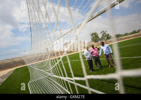 SOMALIA, Mogadischu: Ein Handout Foto vom 12 Januar und veröffentlicht von der hybride Nationen Informationen Support Team 16 Januar zeigt Mitglieder des somalischen Fußball Föderation (SFF) stehen vor ein Ziel-Mund im Baanadir-Stadion im Stadtteil Abd-Aziz von der somalischen Hauptstadt Mogadischu, die vor kurzem mit einer neuen künstlichen Spielfläche wurden wieder aufgetaucht. Finanziert von der FIFA, die FSF hat die 7.500-fassende Stadion neu begrünt und wird in Kürze beginnen Reparaturarbeiten an Plätze, Parkplätze und andere Einrichtungen, die derzeit mit Erinnerungen an Somalia Krieg heimgesuchten Vergangenheit gespickt sind. Stockfoto