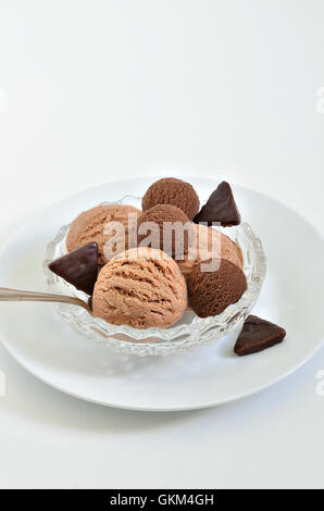 Kugeln Schokoladeneis und Haselnuss-Eis in einer weißen Schüssel, Nahaufnahme, Makro, weißer Hintergrund, vertikale Stockfoto