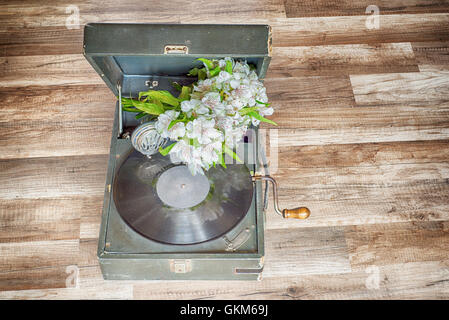 Vintage Plattenspieler Vinyl-Plattenspieler und verwelkten Blumen auf Holzboden Stockfoto