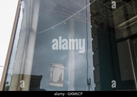 Gebäude spiegeln sich in eine leere Schaufenster front entlang einer Hauptstraße in einer mittleren Innenstadt Stockfoto