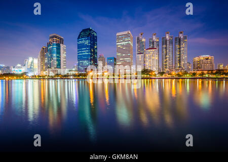 Moderne Wolkenkratzer und Lake Rajada in der Nacht, im Benjakiti Park in Bangkok, Thailand. Stockfoto