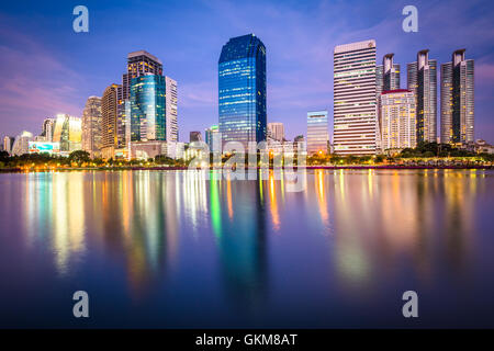 Moderne Wolkenkratzer und Lake Rajada in der Nacht, im Benjakiti Park in Bangkok, Thailand. Stockfoto