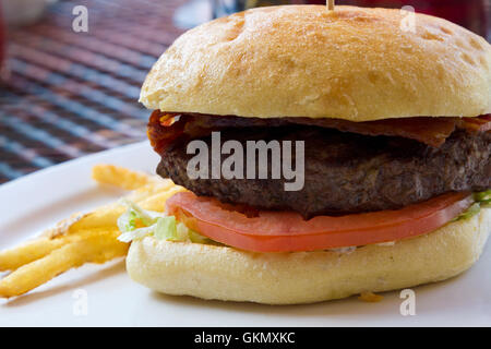 Saftig, gegrillte Hamburger mit gekochten Speckscheiben, Blattsalat und einer frischen Tomaten-Scheibe. Stockfoto