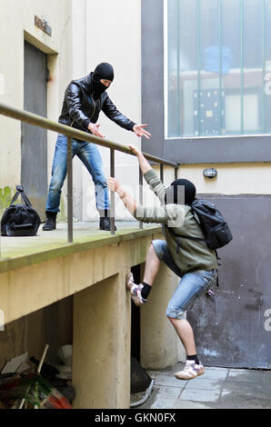 Flucht aus einem Raubüberfall. Man versucht zu helfen, die Schienen zu klettern. Stockfoto