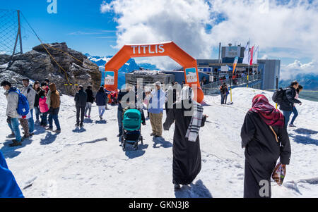 Indischen, asiatischen und arabischen Touristen auf Mount Titlis, Engelberg, Schweiz. Bahnhofsgebäude im Hintergrund. Stockfoto