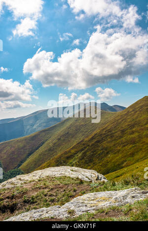 Berglandschaft mit Steinen Verlegung unter dem Rasen oben auf dem Hügel unter dem bewölkten Sommerhimmel Stockfoto