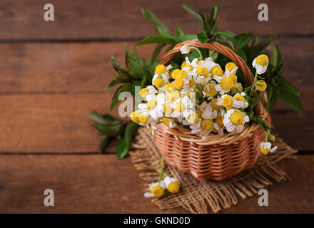 Bouquet von Gänseblümchen in einem Korb auf einem hölzernen Hintergrund Stockfoto