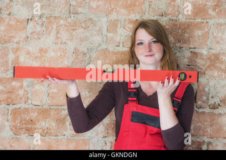 Blick auf eine junge Frau, die eine Wasserwaage. Mauer ist im Hintergrund. Stockfoto