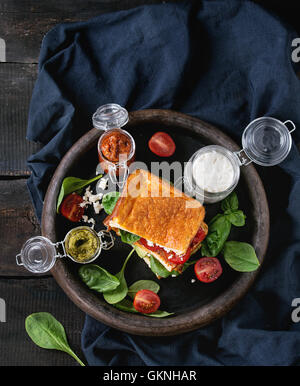 Low-Carb Gluten freie Cloud Brot vegetarischen Sandwich mit Avocado, Spinat, Feta-Käse, Tomaten und Pesto-sauce, serviert auf Lehm tr Stockfoto