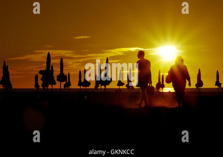 Spektakulären Sonnenuntergang in Deauville-Sur-Mer in Frankreich, mit zwei Personen zu Fuß zwischen den berühmten Sonnenschirme von Deauville Stockfoto