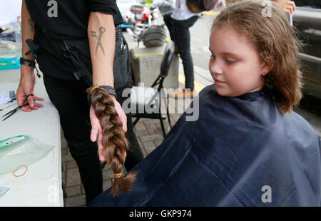 Alajuela, Costa Rica. 21. August 2016. Acht-jährige Lucia Chavez Reyes, spendet ihr Plaid um Perücken für Krebspatienten während einer philanthropischen Veranstaltung von der Ana Ross Foundation in Alajauela, Costa Rica, am 21. August 2016 machen. Familienmitglieder gründete die Stiftung Ana Ross, ein Costa Rica Arzt zu gedenken, die im Jahr 2003 an Krebs gestorben. Ana Ross plädiert für Unternehmen und Hilfe für Krebs-Patienten und sich selbst. © Kent Gilbert/Xinhua/Alamy Live-Nachrichten Stockfoto