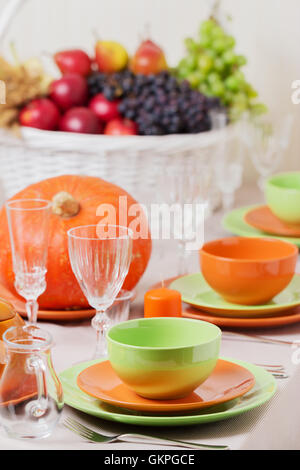 Thanksgiving Day. Festliches Mittagessen mit traditionellen Tischdekoration - Kürbisse, Früchte und Gemüse. Tabelle Einstellung in Orange und Stockfoto