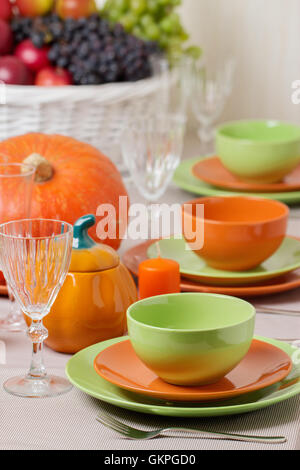 Thanksgiving Day. Festliches Mittagessen mit traditionellen Tischdekoration - Kürbisse, Früchte und Gemüse. Tabelle Einstellung in Orange und Stockfoto