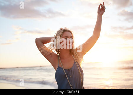 Porträt von attraktiven jungen Frau, die am Strand bei Sonnenuntergang zu genießen. Kaukasische weibliches Model Spaß am Ufer Meeres. Stockfoto