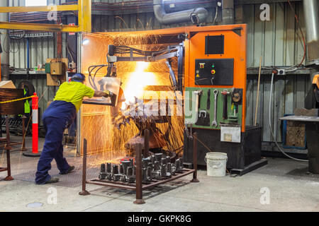 Arbeiter, Schleifen oder Schneiden entfernt werfen Metallkomponenten aus seinem "Casting" Baum. Stockfoto