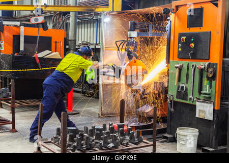 Arbeiter, Schleifen oder Schneiden entfernt werfen Metallkomponenten aus seinem "Casting" Baum. Stockfoto