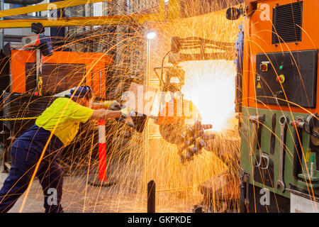 Arbeiter, Schleifen oder Schneiden entfernt werfen Metallkomponenten aus seinem "Casting" Baum. Stockfoto