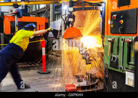 Arbeiter, Schleifen oder Schneiden entfernt werfen Metallkomponenten aus seinem "Casting" Baum. Stockfoto