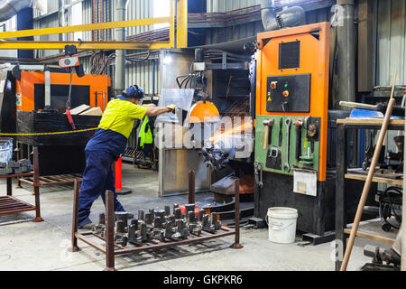 Arbeiter, Schleifen oder Schneiden entfernt werfen Metallkomponenten aus seinem "Casting" Baum. Stockfoto