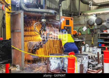 Arbeiter, Schleifen oder Schneiden entfernt werfen Metallkomponenten aus seinem "Casting" Baum. Stockfoto