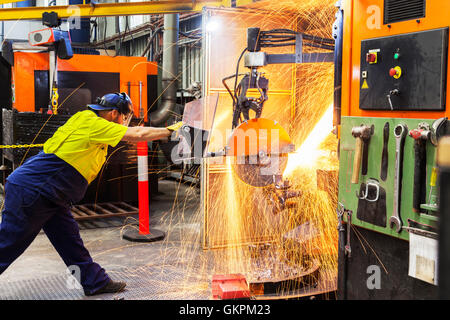 Arbeiter, Schleifen oder Schneiden entfernt werfen Metallkomponenten aus seinem "Casting" Baum. Stockfoto