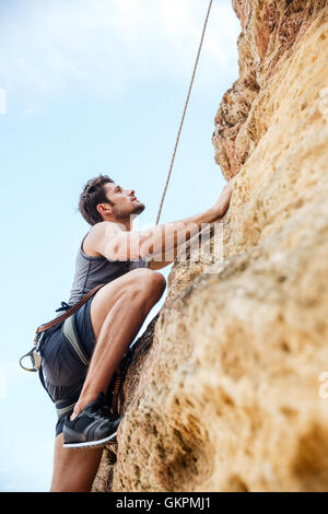 Junge hübsche Sportler eine Felswand erklimmen Stockfoto