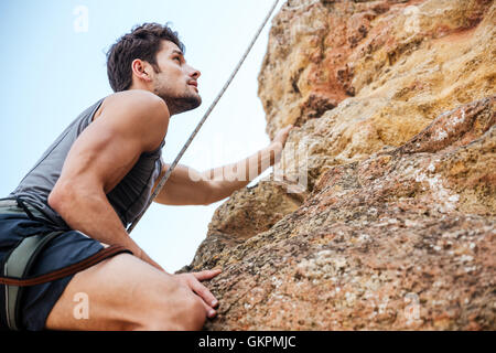 Junge hübsche Sportler eine Felswand erklimmen Stockfoto