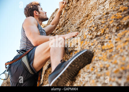 Junge hübsche Sportler eine Felswand erklimmen Stockfoto