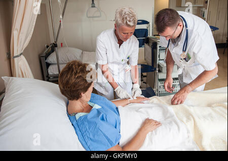 Verpleegkundigen Sluiten Een Infuus Aan Bij de Patienten. De Verpleegkundige Plakken de Infuusnaald af de Sluite Het Infuus Aan. Stockfoto