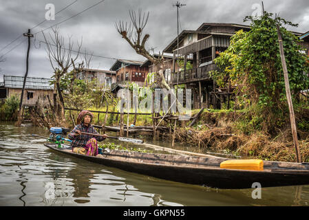 Frau des Stammes Inthar Bootfahren durch ihr Dorf.  Inthar Menschen bauen Holzhäuser auf Pfählen am See Leben. Stockfoto